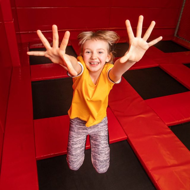 Happy little girl having fun while jumping on trampoline